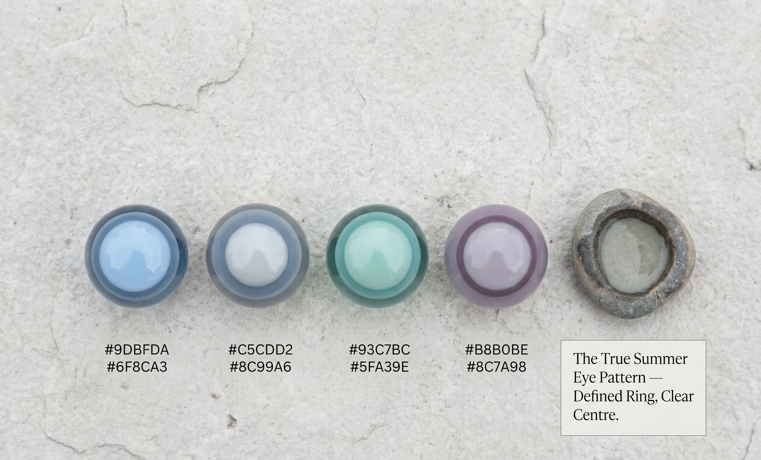 Four glass marbles each showing a lighter central colour with a clearly defined darker outer ring — illustrating the True Summer eye pattern of blue, blue-grey, blue-green, and cool-violet eyes with crisp limbal ring definition